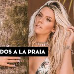 Mulher com cabelo solto, apoiada em árvore, usando acessórios e com texto "Os penteados a La Praia" ao fundo.