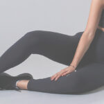 Mulher usando legging preta e top cropped, sentada em posição relaxada.