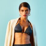 Mulher usando biquíni brilhante com blazer, destacando estilo versátil para além da praia.