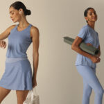 Mulher usando roupas de treino azuis, com top e saia, segurando um tapete de yoga.